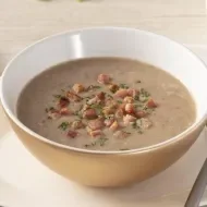 As melhores comidas de Inverno Sopa de feijão na tigela em cima de um prato, ao lado uma colher